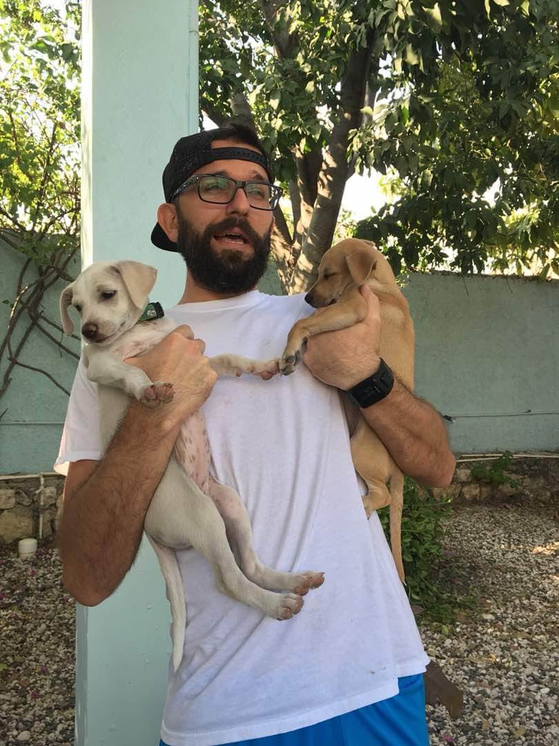Eric Padron holding two cute puppies in Haiti